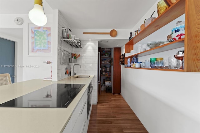 kitchen featuring backsplash, sink, black electric cooktop, dark hardwood / wood-style flooring, and white cabinetry