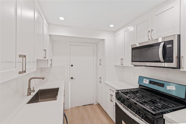 kitchen with decorative backsplash, stainless steel appliances, sink, light hardwood / wood-style flooring, and white cabinetry