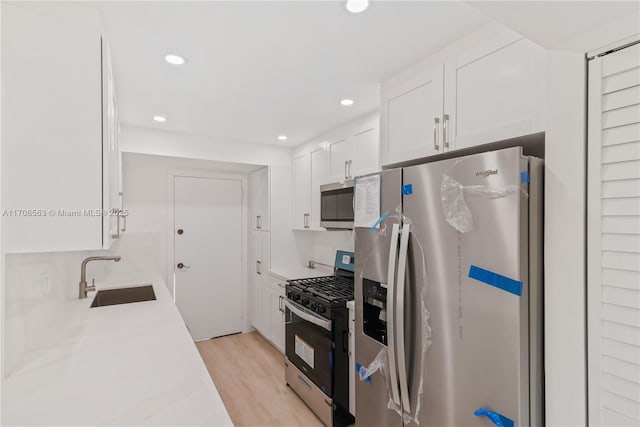 kitchen featuring sink, white cabinets, stainless steel appliances, and light hardwood / wood-style floors