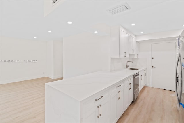 kitchen with white cabinetry, dishwasher, light wood-type flooring, and sink