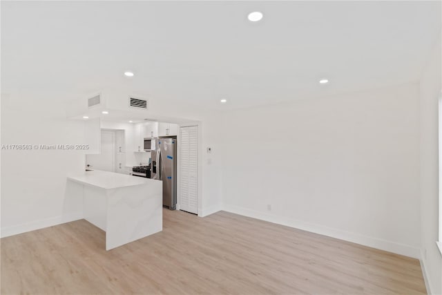 kitchen with stainless steel fridge, light wood-type flooring, white cabinetry, and kitchen peninsula