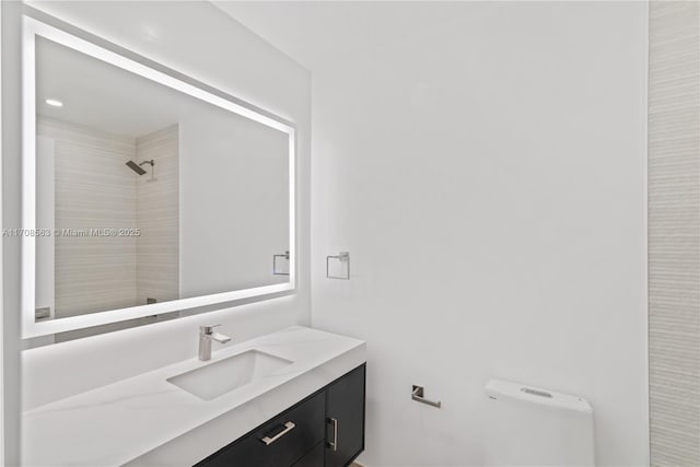 bathroom with a tile shower and vanity