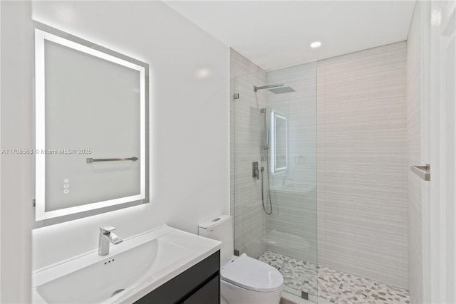 bathroom with a tile shower, vanity, and toilet