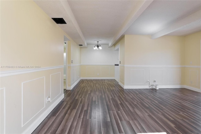 empty room featuring beam ceiling, a textured ceiling, dark hardwood / wood-style floors, and a notable chandelier