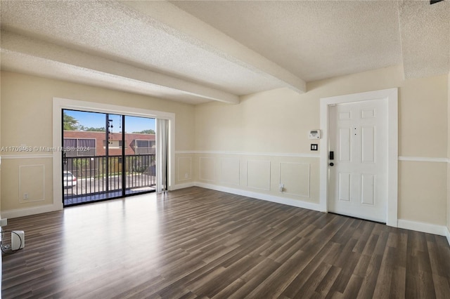 unfurnished room featuring a textured ceiling, beamed ceiling, and dark hardwood / wood-style floors