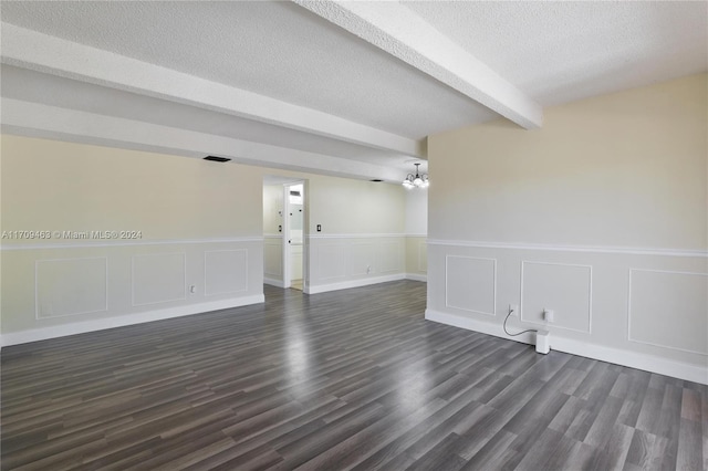 empty room featuring beamed ceiling, dark hardwood / wood-style flooring, a textured ceiling, and an inviting chandelier