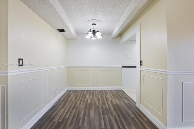 unfurnished dining area with a chandelier, a textured ceiling, and dark hardwood / wood-style flooring