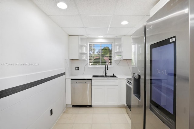 kitchen featuring appliances with stainless steel finishes, a paneled ceiling, white cabinetry, and sink