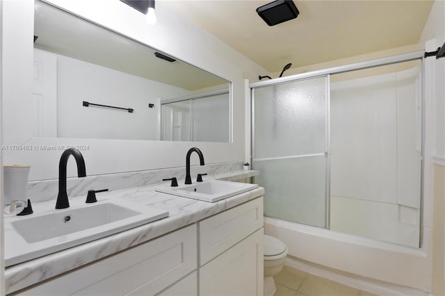 full bathroom featuring tile patterned floors, vanity, bath / shower combo with glass door, and toilet