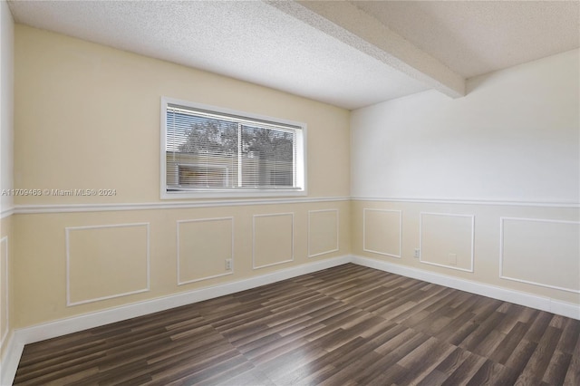 unfurnished room with beam ceiling, dark hardwood / wood-style flooring, and a textured ceiling