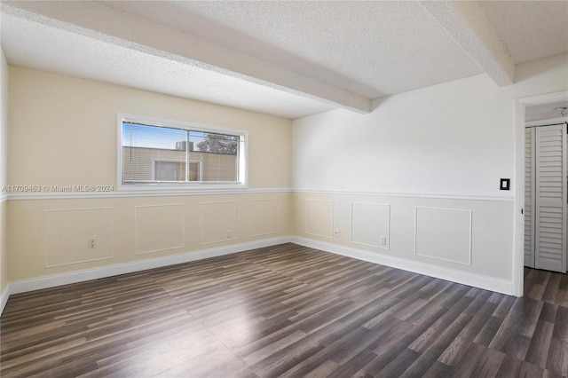 unfurnished room featuring beamed ceiling, a textured ceiling, and dark hardwood / wood-style flooring