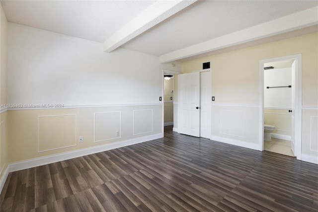 empty room featuring dark hardwood / wood-style floors and beam ceiling