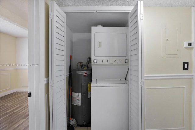 washroom with a textured ceiling, electric water heater, hardwood / wood-style flooring, and stacked washer / drying machine