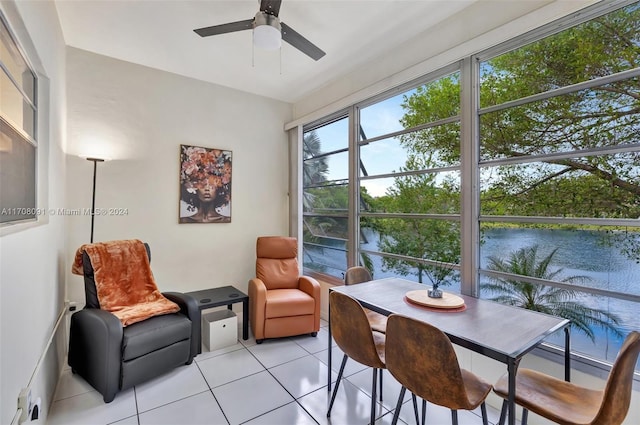 sunroom featuring a water view and ceiling fan