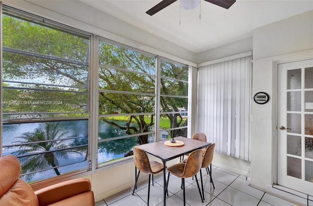 sunroom featuring ceiling fan and a water view