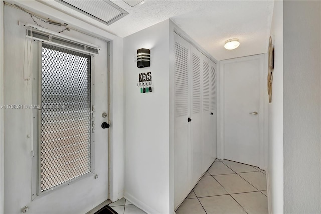 doorway to outside with light tile patterned flooring and a textured ceiling