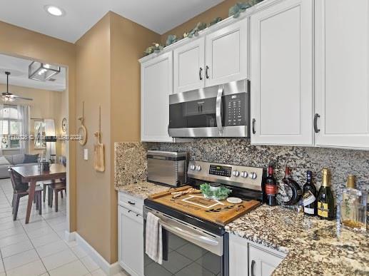 kitchen featuring white cabinetry, ceiling fan, decorative backsplash, light tile patterned floors, and appliances with stainless steel finishes