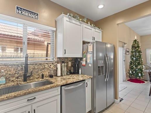 kitchen with white cabinets, decorative backsplash, sink, and stainless steel appliances