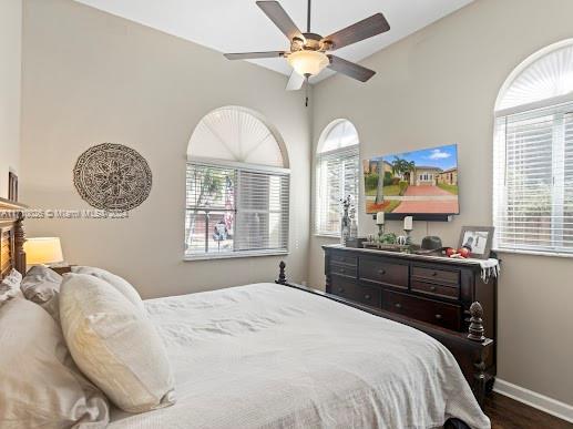 bedroom with ceiling fan, dark wood-type flooring, and multiple windows