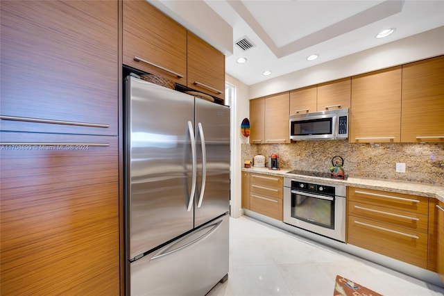 kitchen featuring light tile patterned floors, light stone countertops, backsplash, and appliances with stainless steel finishes