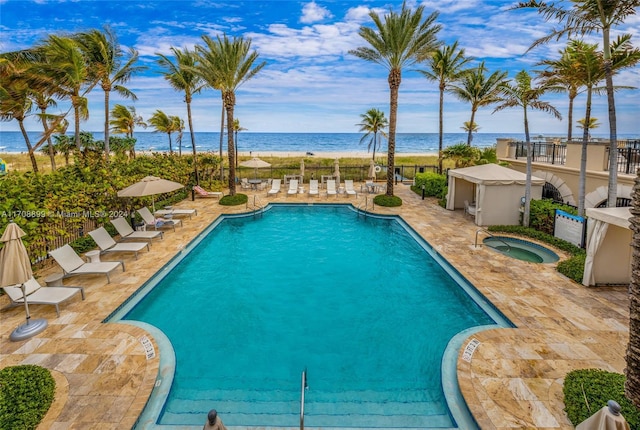 view of pool featuring a patio area, a water view, and a hot tub