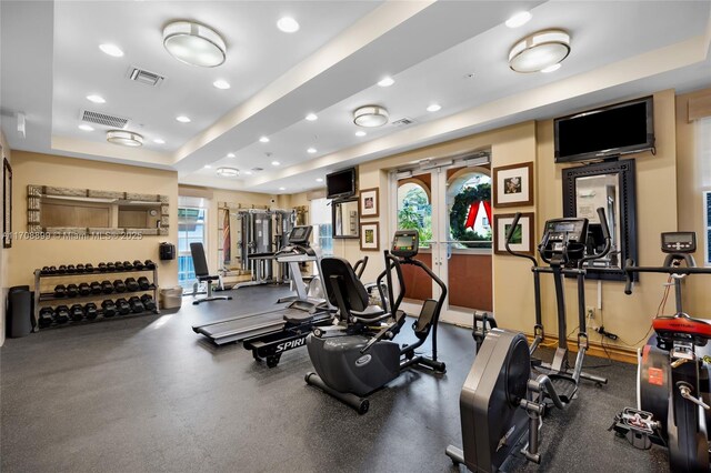 exercise room with french doors and a raised ceiling