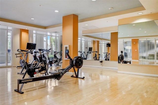 gym with light hardwood / wood-style floors and a raised ceiling