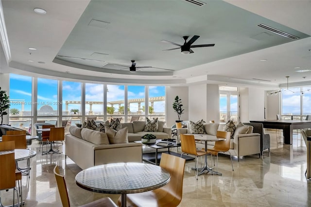 living room featuring ceiling fan, a raised ceiling, and a wealth of natural light