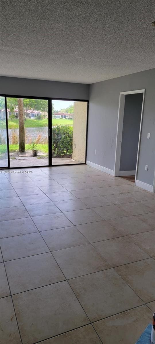 spare room with a textured ceiling, plenty of natural light, and light tile patterned flooring