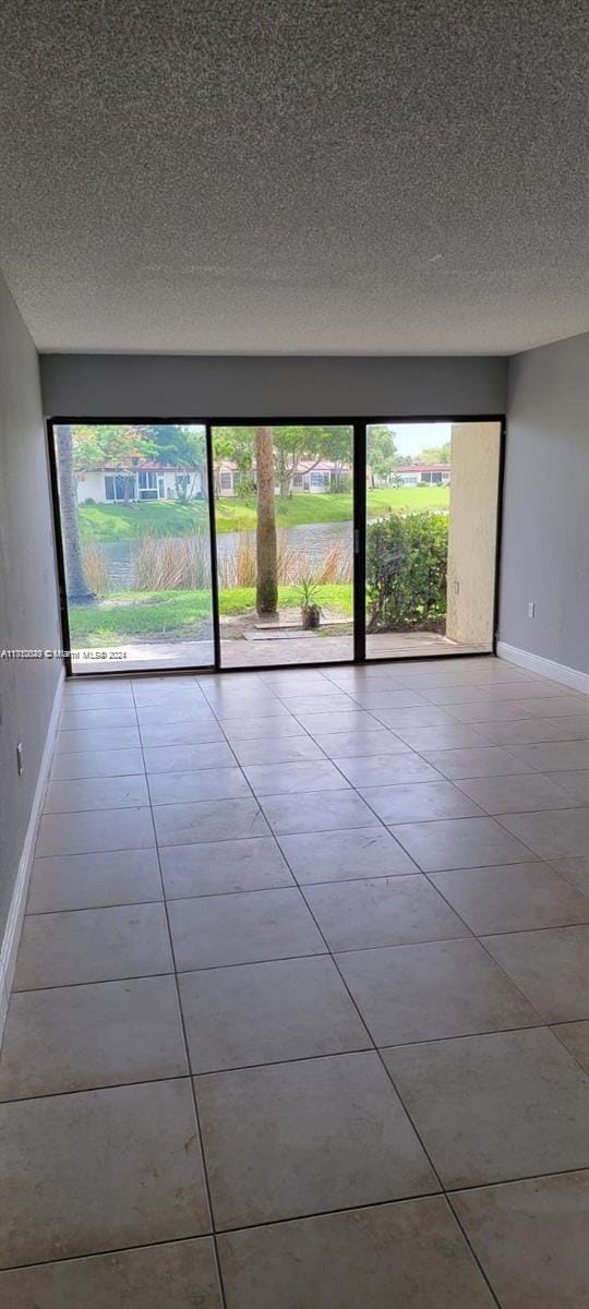 tiled empty room with a textured ceiling