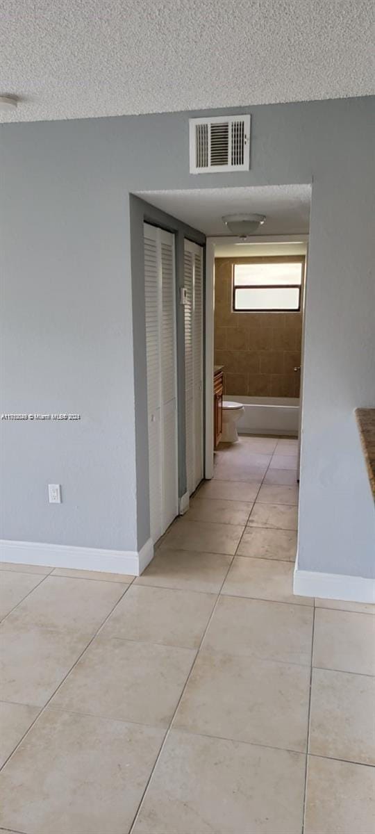 hall with light tile patterned floors and a textured ceiling