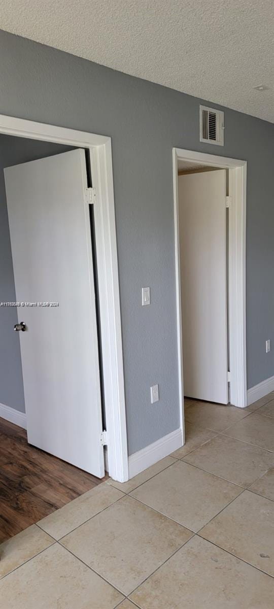 spare room featuring light hardwood / wood-style floors and a textured ceiling