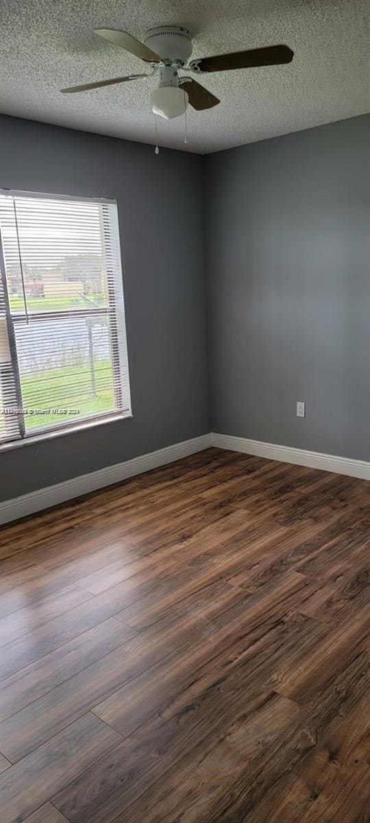 empty room featuring a textured ceiling and dark hardwood / wood-style floors