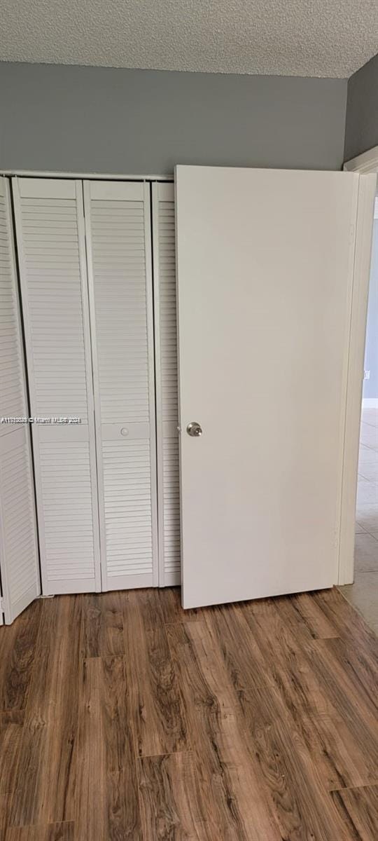 unfurnished bedroom with wood-type flooring, a textured ceiling, and a closet