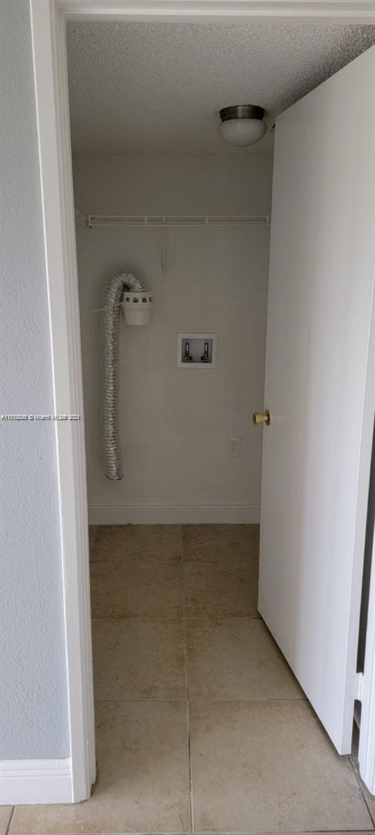 laundry room with hookup for a washing machine, a textured ceiling, and light tile patterned floors