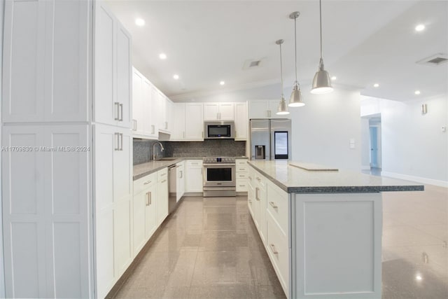 kitchen featuring white cabinets, a kitchen island, stainless steel appliances, and vaulted ceiling