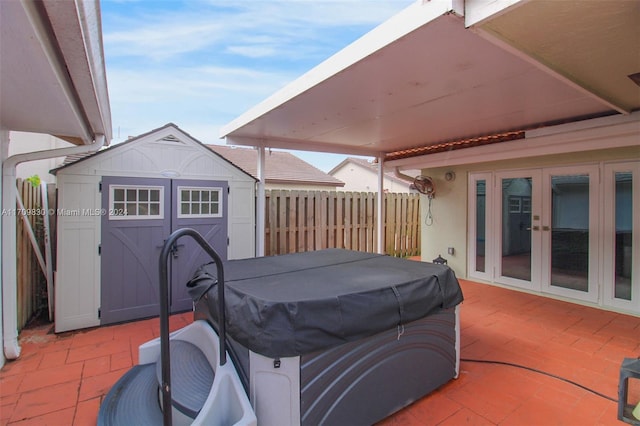 view of patio / terrace with french doors, a hot tub, and a storage shed