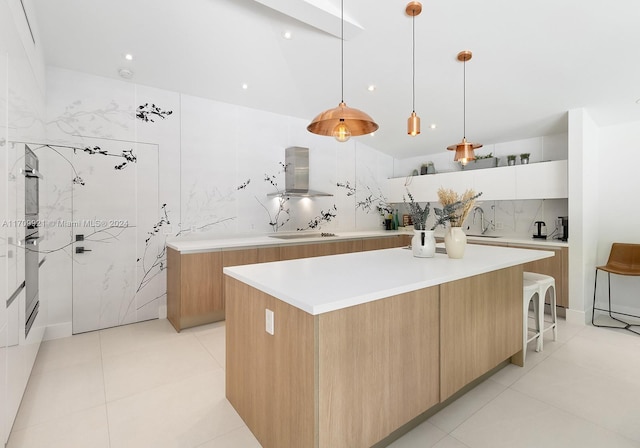 kitchen featuring backsplash, wall chimney exhaust hood, a spacious island, decorative light fixtures, and white cabinetry