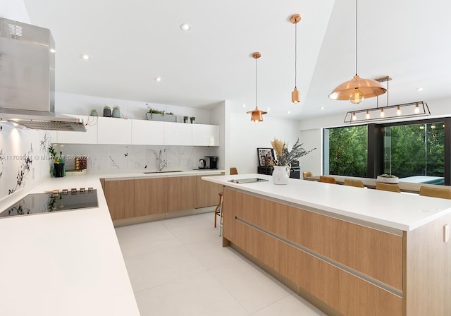 kitchen featuring black electric cooktop, sink, decorative light fixtures, white cabinets, and range hood