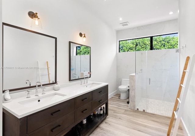 bathroom with toilet, vanity, a shower with door, and hardwood / wood-style flooring