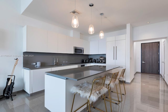 kitchen with a breakfast bar, white cabinetry, sink, and a kitchen island