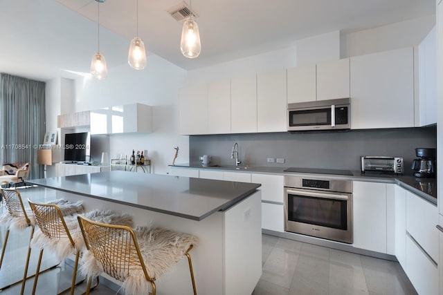 kitchen featuring white cabinets, appliances with stainless steel finishes, and a breakfast bar area