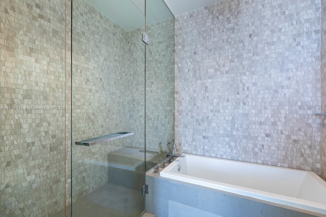 bathroom with tile walls and independent shower and bath