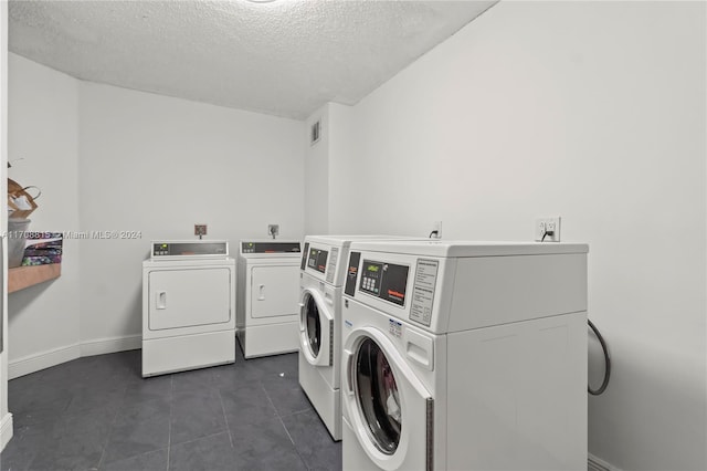 laundry room with dark tile patterned flooring, washer and dryer, and a textured ceiling