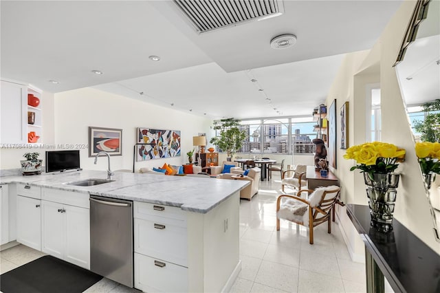 kitchen featuring light stone counters, sink, white cabinets, and stainless steel dishwasher