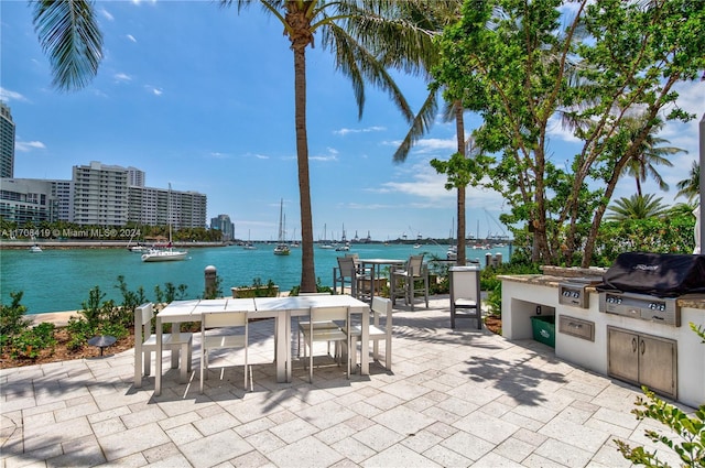 view of patio featuring area for grilling, a water view, and exterior kitchen