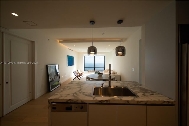 kitchen featuring sink, decorative light fixtures, light wood-type flooring, dishwasher, and light stone countertops