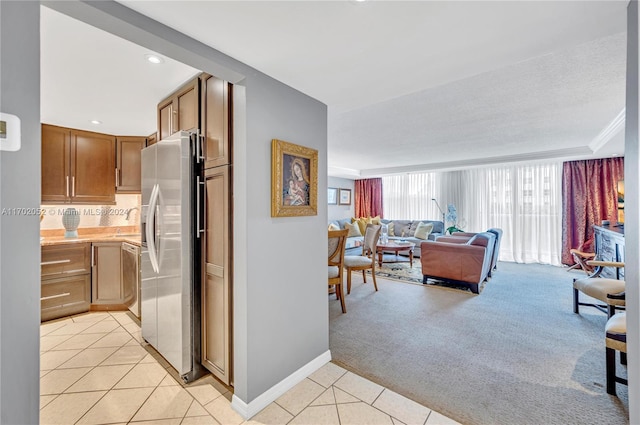 kitchen featuring stainless steel refrigerator with ice dispenser, tasteful backsplash, ornamental molding, and light colored carpet