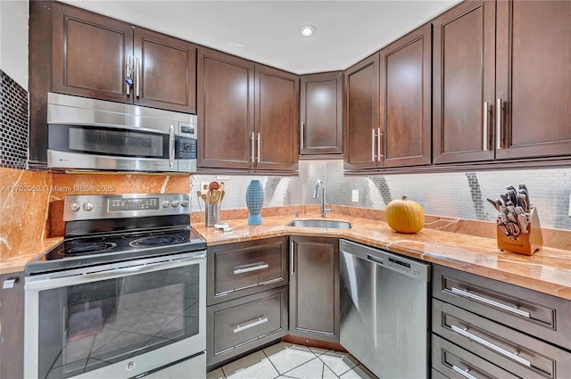 kitchen featuring decorative backsplash, appliances with stainless steel finishes, dark brown cabinets, a sink, and light tile patterned floors