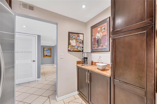 interior space featuring dark brown cabinetry, light tile patterned floors, and sink